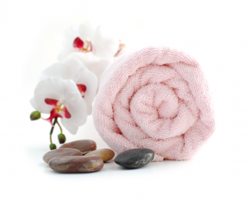 Een handoek met massage stenen en een rustgevende bloem in de kleur van sashibeauty